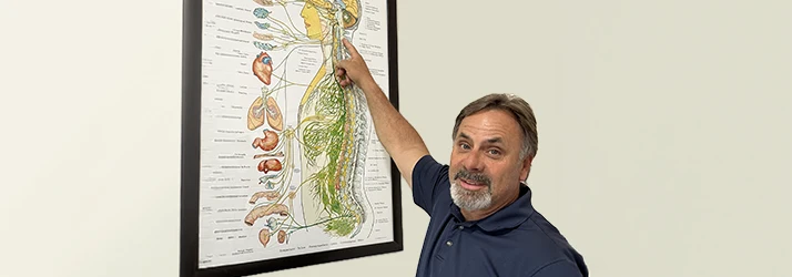 Richard Doble Smiling and Pointing at an Anatomy Poster